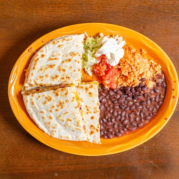 A quesadilla with rice, black beans, lettuce, diced tomatoes, and sour cream on an orange plate.