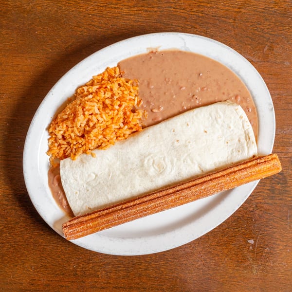 Burrito plate with rice, refried beans, and a churro on a white oval plate.