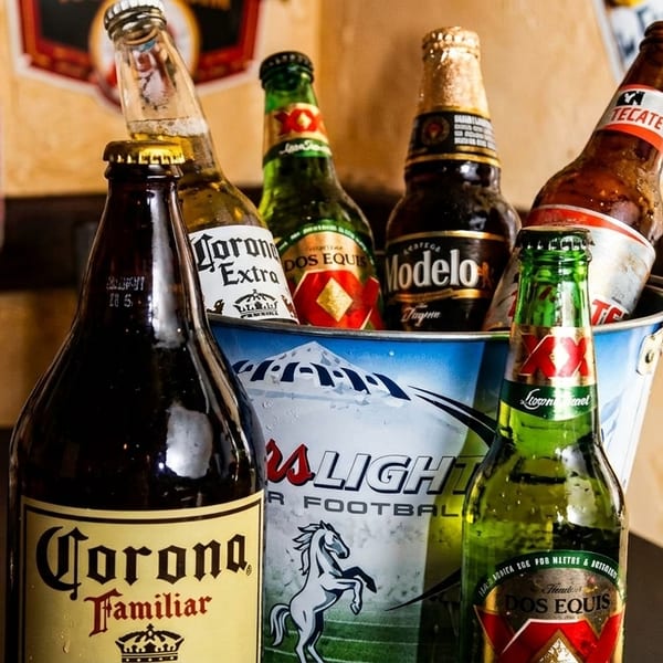A bucket of assorted Mexican beer bottles, including Corona, Modelo, Dos Equis, and Tecate.