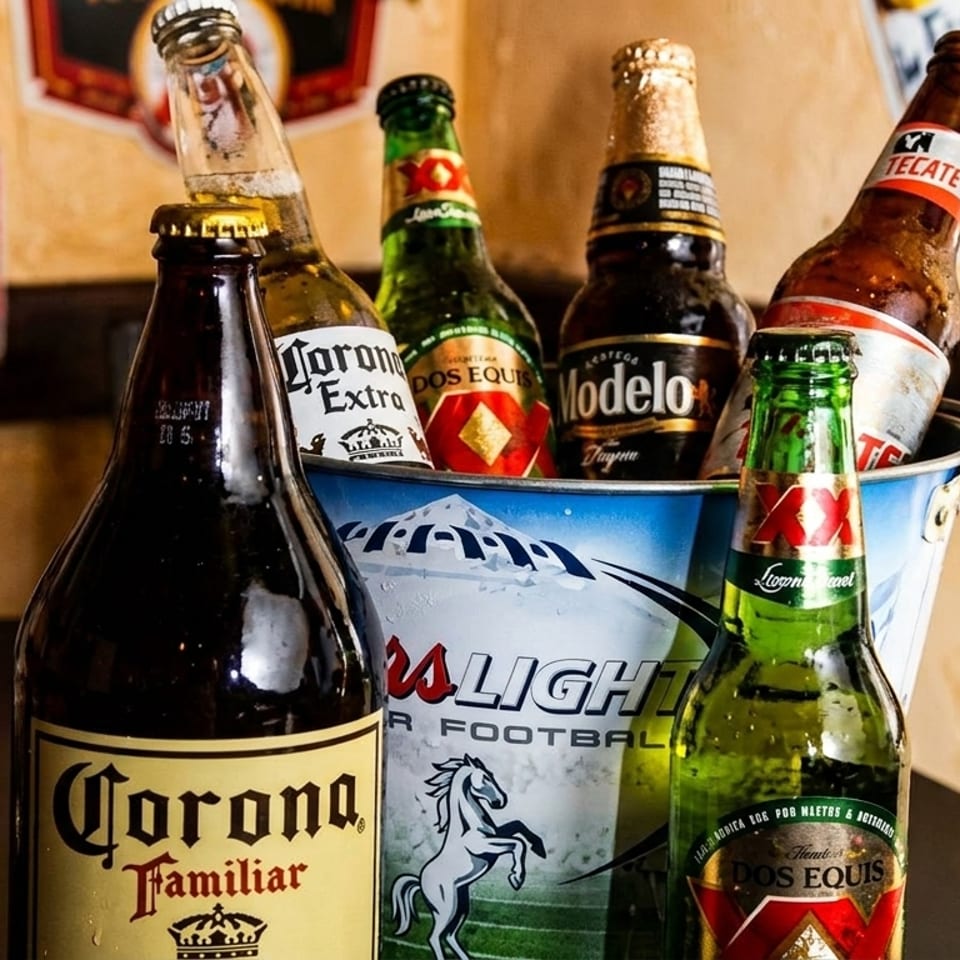 A bucket of assorted Mexican beer bottles, including Corona, Modelo, Dos Equis, and Tecate.