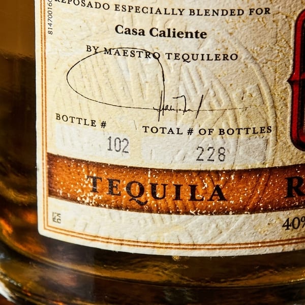 Close-up of a tequila bottle label, showing "Casa Caliente" and "Tequila Reposado".