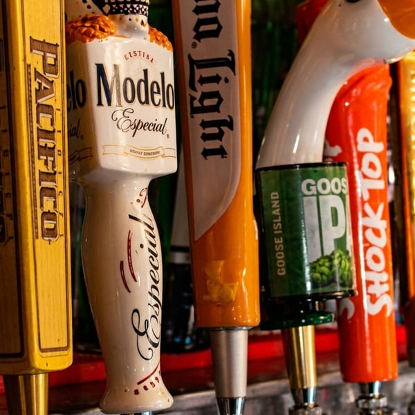 A close-up of various beer tap handles, including Modelo Especial, Pacifico, Bud Light, and Goose Island.