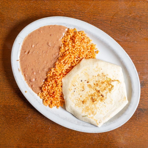 A burrito, refried beans, and Spanish rice are served on a white oval plate.