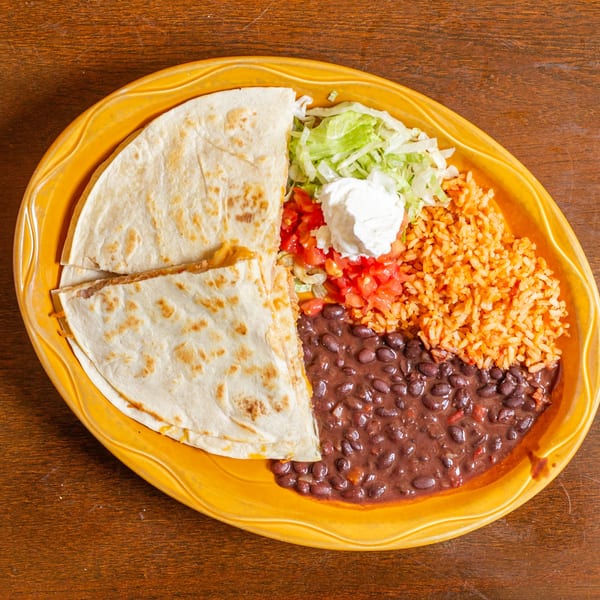 A quesadilla with rice, black beans, lettuce, tomatoes, and sour cream on a yellow plate.